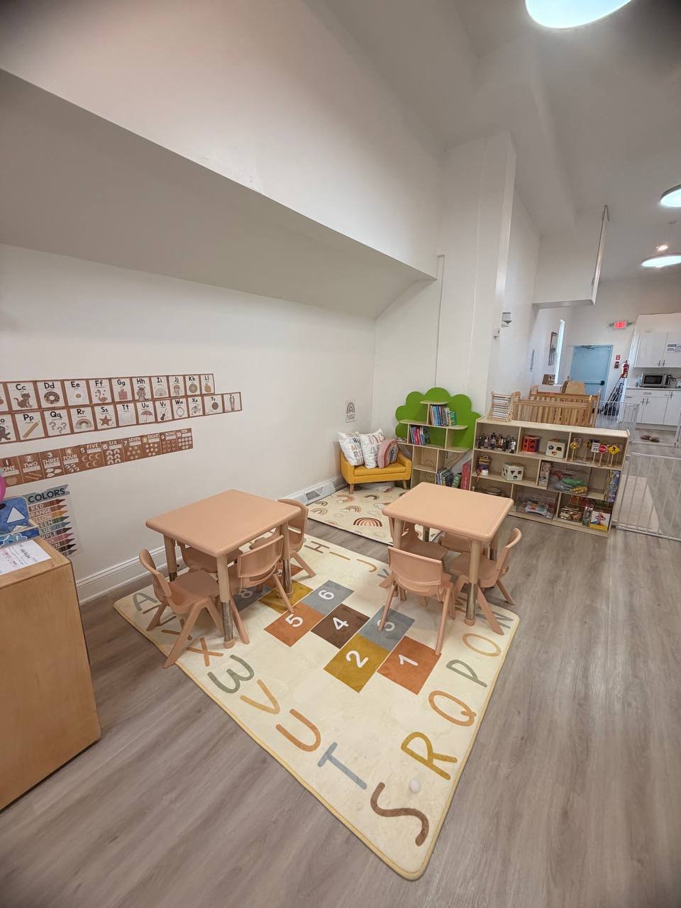 Open classroom with learning tables and soft activity rugs